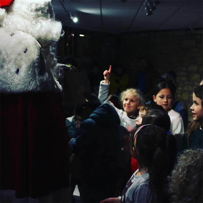 Father Christmas speaking to Grotto Visitors with one guest asking a question